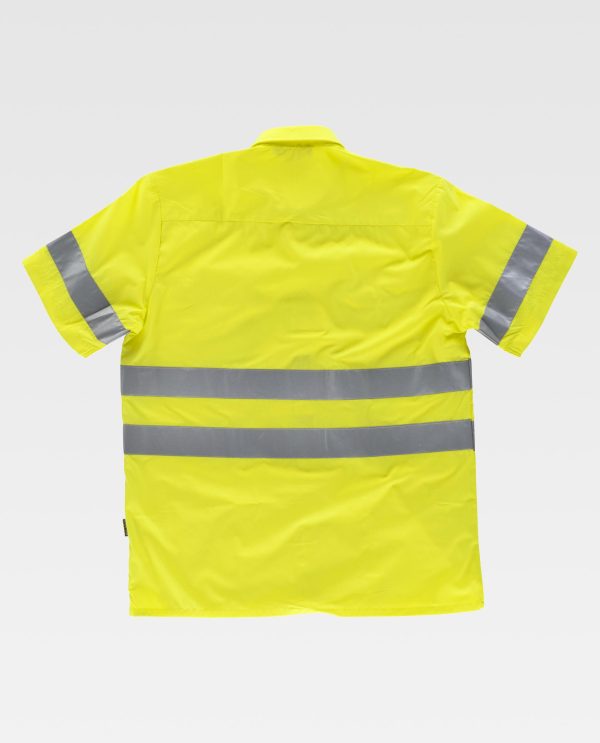 Miliar Ropa Laboral Camisa de alta visibilidad de manga corta con cintas reflectantes. Cuello clásico y cierre central de botones. Dos bolsos en pecho de plastón con cartera de botón. Una cinta reflectante en mangas y dos en pecho y espalda. Espalda con canesú. Botones al tono.